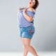 Plus size fashion model in jean shorts woman on gray background