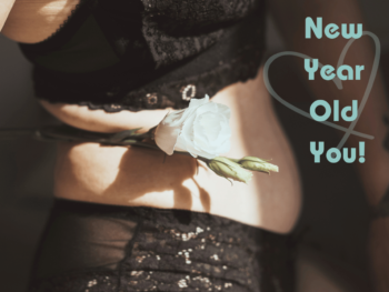 side close up of a female torso in black underwear. She holds a white rose in her waist. Text reads 'New Year Old You!' with a faint heart shape in the background.